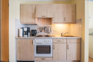 cocina con armarios de madera y horno con fogones en Haus Seemeile Wohnung 2 20, en Büsum