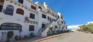 biały budynek z wieloma oknami na ulicy w obiekcie Casa Clare, Cabo Roig w mieście Cabo Roig