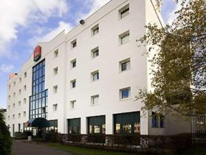 um grande edifício branco com muitas janelas em ibis Paris Le Bourget em La Courneuve