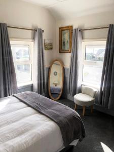 um quarto com uma cama, um espelho e uma cadeira em Westend Bar & Restaurant em Fenit