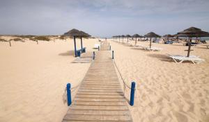 un camino de madera en una playa con sombrillas y sillas en Luxury Townhouse, in Tavira Centre with shared pool, en Tavira