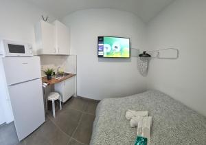 a small white kitchen with a bed and a refrigerator at Mini Estudio JACUZZI DOBLE SEVILLA "POLIGONO INDUSTRIAL" in Seville