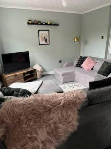 a living room with a couch and a television at Modern cosy home sleeps 6 with parking nr Preston in Leyland