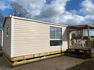 a large white tiny house with a porch at Camping de Contrexeville in Contrexéville