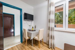 a dining room with a table and chairs and a tv at Guest House Marinna in Vrboska