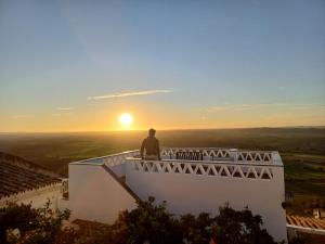 een man die op een balkon staat te kijken naar de zonsondergang bij Casa Dona Antonia - Monsaraz in Monsaraz