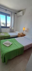 sypialnia z 2 łóżkami z zieloną pościelą i oknem w obiekcie Casa Clare, Cabo Roig w mieście Cabo Roig