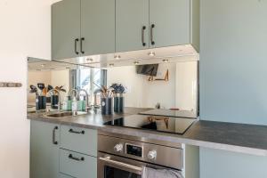 Una cocina con gabinetes blancos y electrodomésticos de acero inoxidable. en L'Orée des Aravis - Au pied des pistes, en Manigod