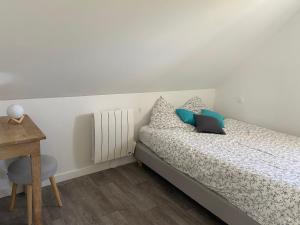 a bedroom with a bed with blue pillows and a desk at Ty Eurvad - Proche des plages in Bangor