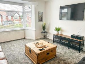uma sala de estar com uma mesa de centro e uma televisão de ecrã plano em Highcross em Poulton le Fylde