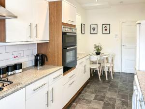 a kitchen with white cabinets and a table with chairs at Highcross in Poulton le Fylde