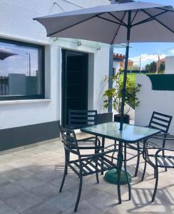 a table and chairs with an umbrella on a patio at Casa Pátio country house in Enxara do Bispo
