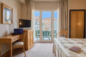 ein Hotelzimmer mit Bett, Schreibtisch und Fenster in der Unterkunft Hotel Macià Cóndor in Granada