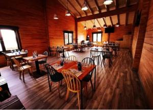 un restaurante con suelo de madera, mesas y sillas en Kampaoh Somo Parque en Somo