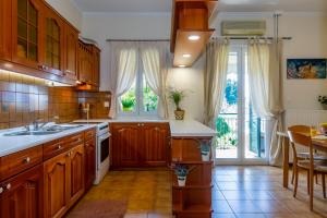 a kitchen with wooden cabinets and a large window at Casa Loula in Corfu