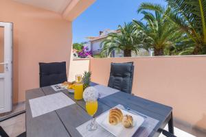 a table with bread and orange juice on a balcony at Guest House Marinna in Vrboska