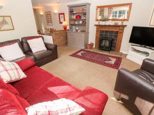 a living room with a red couch and a fireplace at Beach Way Cottage in Gorran Haven