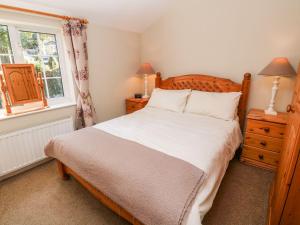 a bedroom with a large bed and a window at Beach Way Cottage in Gorran Haven