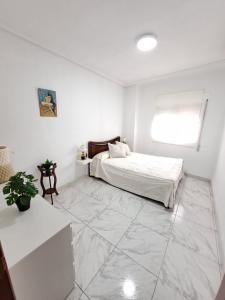 Habitación blanca con cama y ventana en Piso céntrico y tranquilo, en Madrid