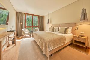 a bedroom with a bed and a desk in a room at PortoBay Serra Golf in Santo da Serra