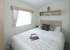 a bedroom with a white bed and a window at Burrowhead Holiday Village in Isle of Whithorn