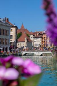 most nad rzeką w mieście z fioletowymi kwiatami w obiekcie La Résidence I Cœur vieille ville w Annecy
