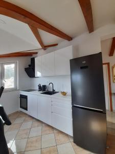 a kitchen with a stainless steel refrigerator and white cabinets at Villa-kuća za odmor "RATAC" in Bol