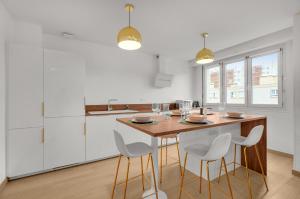 a kitchen with a wooden table and white cabinets at Le Synopsis - Joli T3 avec garage in Toulouse