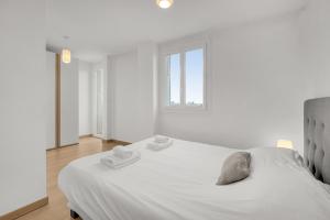 Un dormitorio blanco con una cama grande y una ventana en Le Synopsis - Joli T3 avec garage, en Toulouse