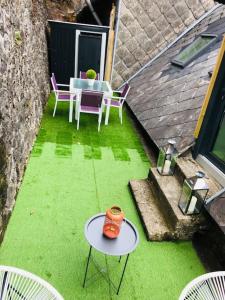 une terrasse avec une table et des chaises sur de l'herbe verte dans l'établissement Maison de vacances, à La Bourboule