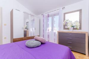 ein Schlafzimmer mit einem lila Bett und einer Kommode in der Unterkunft Apartmani Selo Luka in Ražanj