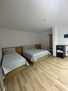 1 dormitorio con 2 camas y suelo de madera en Hotel Verzaci, en Rinas