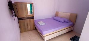 ein kleines Schlafzimmer mit einem lila Bett in einem Zimmer in der Unterkunft Brak Homestay in Sukobumi