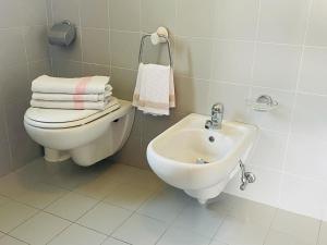 Baño blanco con aseo y lavamanos en Foresteria Miramonti affittacamere, en Fiavè