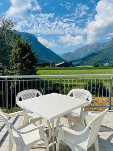 una mesa blanca y sillas en un balcón con montañas en Foresteria Miramonti affittacamere, en Fiavè