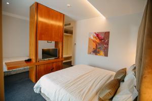 1 dormitorio con 1 cama, armario y TV en Hotel Delta en Durrës