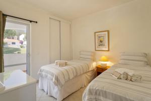 dwa łóżka w pokoju z oknem w obiekcie Villa Flamingo w mieście Vale do Lobo