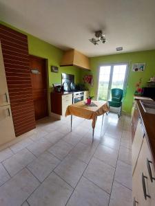 eine Küche mit grünen Wänden und einem Tisch im Zimmer in der Unterkunft Maison de 4 chambres avec jardin clos et wifi a Roncherolles en Bray in Mauquenchy