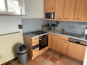 a kitchen with wooden cabinets and a sink and a trash can at Op adem komen op de mooiste plek in het heuvelland-De Boswachter in Vijlen