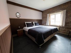 a bedroom with a large bed with a brick wall at Op adem komen op de mooiste plek in het heuvelland-De Boswachter in Vijlen