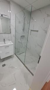 ein weißes Bad mit einer Dusche und einem Waschbecken in der Unterkunft Street C apartment nr 2 in Pristina