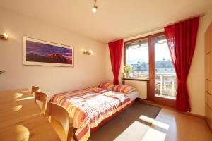 1 dormitorio con 1 cama y una ventana con cortinas rojas en Haus Wendland, en Bischofswiesen