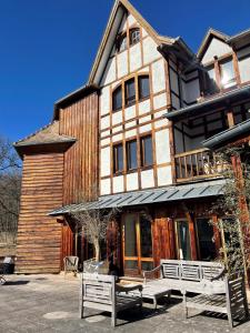 a large wooden building with benches in front of it at Les appartements du Manoir des Sens in Thannenkirch