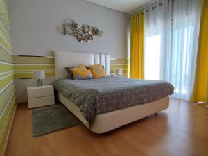 a bedroom with a large bed with yellow curtains at Sunset Street Beach house in Lourinhã