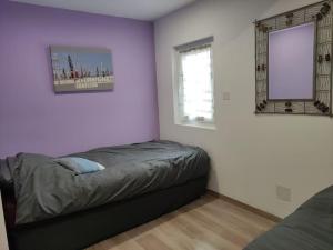 ein Schlafzimmer mit lila Wänden und einem Bett darin in der Unterkunft Le grand gîte d'Angélique en Normandie - 4 personnes in Norville