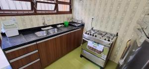 a small kitchen with a stove and a sink at Linda Casa com Piscina - Praia do Pernambuco - Guarujá in Guarujá