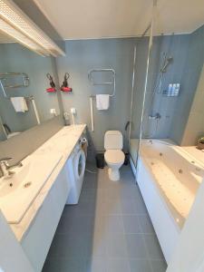 a bathroom with a toilet and a tub and a washing machine at City Apartment 302 in Loviisa