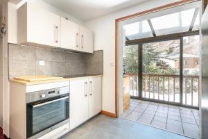 a kitchen with white cabinets and a large window at Le Chalet in Les Deux Alpes