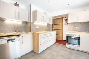 una cocina con armarios blancos y electrodomésticos blancos en Le Chalet, en Les Deux Alpes
