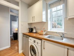 a kitchen with a washing machine and a sink at Wisteria Cottage in Horam